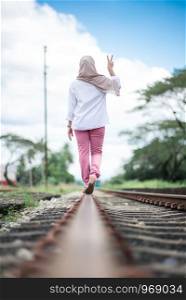 young woman walking on railroad tracks