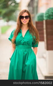 Young woman walking outdoors in the the city. Young woman in green dress in the city