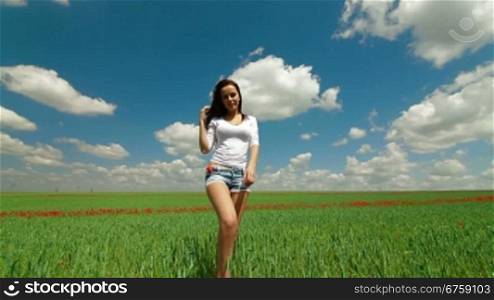 Young Woman Walking Through Green Wheat Field. Front View