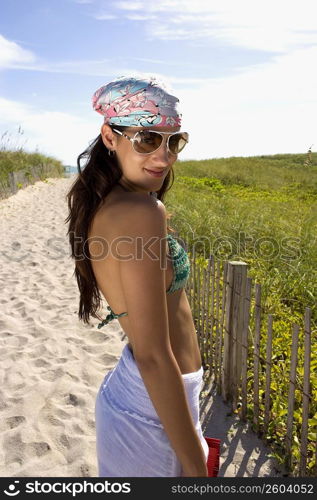 Young woman walking up path on beach