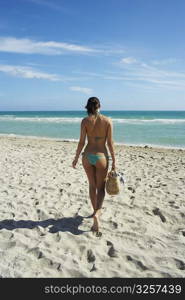 Young woman walking with beach bag on beach