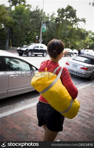 Young woman walking with duffel bag