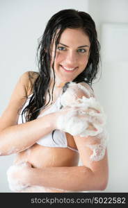 Young woman washing body with shower gel at home or hotel