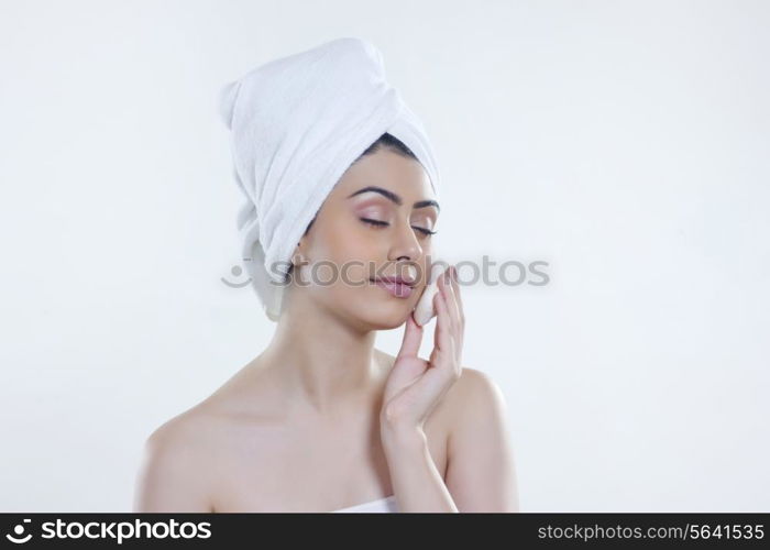 Young woman washing face with soap bar against white background