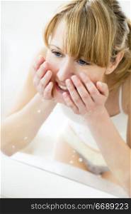 young woman washing her face in a basin and looking herself in the mirror