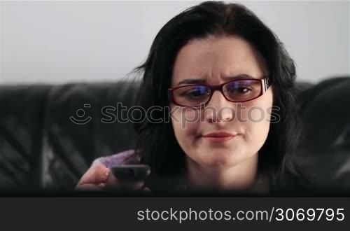 Young woman watching boring movie at TV
