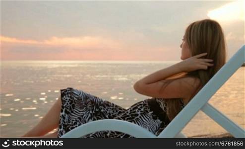 young woman watching sunset at the beach by the sea