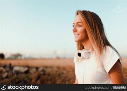 Young woman watching sunset with her headphones on the field