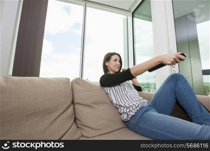 Young woman watching TV on sofa at home