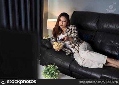 young woman watching TV on sofa at night