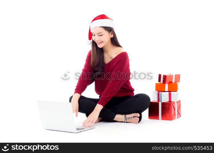 Young woman wear santa hat and gift box sitting labtop with internet shopping in season christmas holiday, girl shoping online on notebook in xmas, celebration concept.