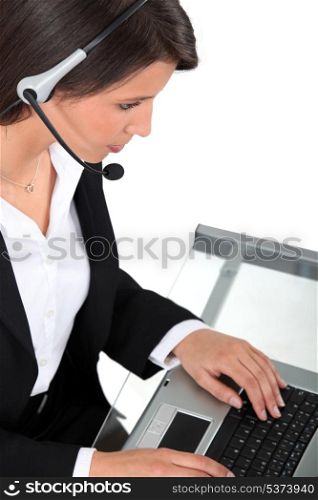 Young woman wearing a headset typing at a keyboard