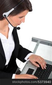 Young woman wearing a headset typing at a keyboard