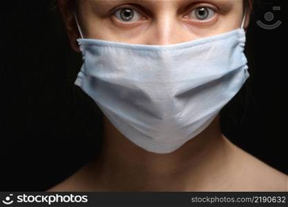 Young woman wearing a protective mask during the Coronavirus disease COVID-19 outbreak epidemic. Close up studio portrait on a black background. Young woman wearing a protective mask during the Coronavirus disease COVID-19 outbreak epidemic. Close up studio portrait on a black background.