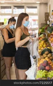 Young woman wearing a surgical mask using plastic gloves to pick up fruits at a grocery store. Safety and shopping concept.. woman wearing a surgical mask using plastic gloves to pick up fruits. Safety and shopping concept.