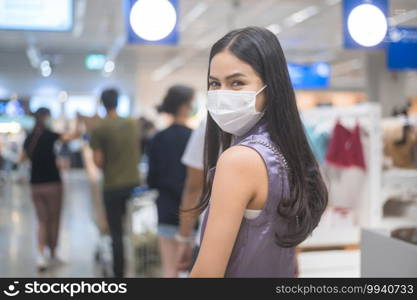 young woman wearing a surgical mask waiting in line near cashier counter in supermarket, covid-19 and pandemic concept