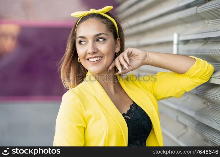 Young woman wearing a yellow jacket and headband in urban background. Young woman wearing a yellow jacket and headband