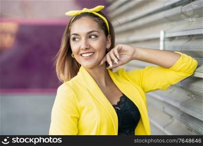 Young woman wearing a yellow jacket and headband in urban background. Young woman wearing a yellow jacket and headband