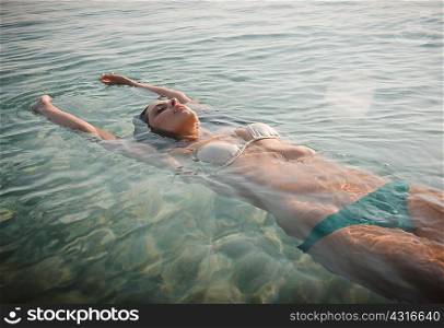 Young woman wearing bikini floating in sea