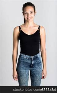 Young woman wearing black tank top and blue jeans on white background. Gir smiling. Studio shot