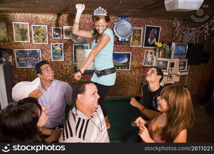 Young woman wearing crown dancing on billiard table