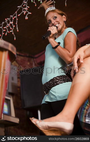 Young woman wearing crown signing at Karaoke bar