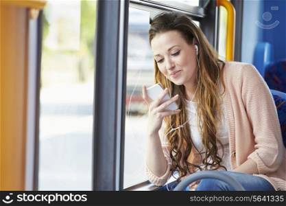Young Woman Wearing Earphones Listening To Music On Bus