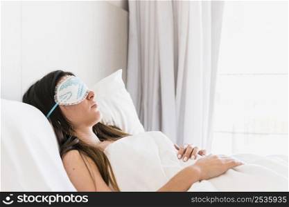 young woman wearing eye mask sleeping bed bedroom