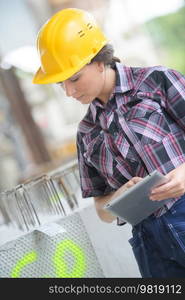 young woman wearing hardhat safety helmet while using a tablet