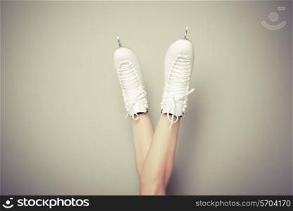 Young woman wearing ice skates with her legs up against a wall