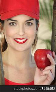 Young woman wearing red cap with apple in her hand