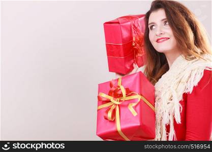 Young woman wearing red dress warm woolen shawl holding presents two gift boxes with ribbon. Christmas season celebration concept.. Woman holds red christmas gift boxes