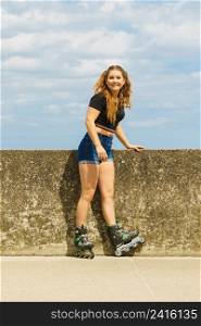 Young woman wearing roller skates outdoor. Fashionable fit girl having fun at sunny summer day.. Fit girl with roller skates outdoor