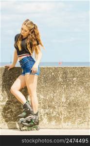 Young woman wearing roller skates outdoor. Fashionable fit girl having fun at sunny summer day.. Fit girl with roller skates outdoor
