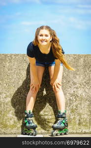 Young woman wearing roller skates outdoor. Fashionable fit girl having fun at sunny summer day.. Fit girl with roller skates outdoor