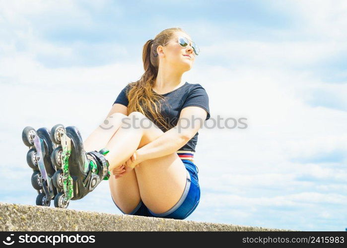 Young woman wearing roller skates outdoor. Fashionable fit girl having fun resting at sunny summer day.. Fit girl with roller skates outdoor