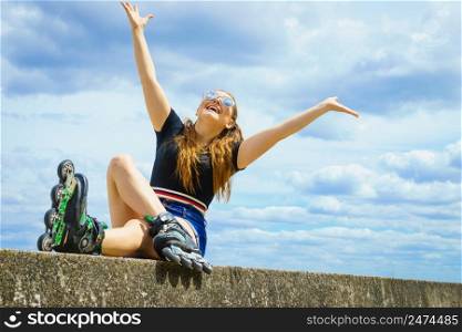 Young woman wearing roller skates outdoor. Fashionable fit girl having fun resting at sunny summer day.. Fit girl with roller skates outdoor