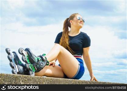 Young woman wearing roller skates outdoor. Fashionable fit girl having fun resting at sunny summer day.. Fit girl with roller skates outdoor