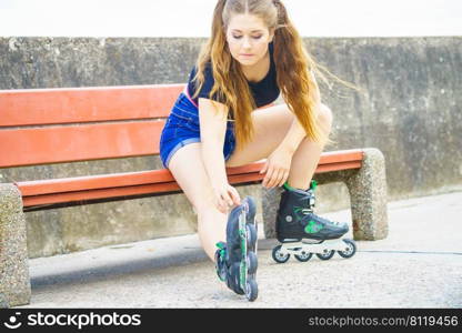 Young woman wearing roller skates outdoor. Fashionable fit girl having fun resting on bench.. girl with roller skates outdoor