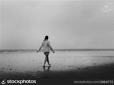 Young woman wearing sweater walking on beach
