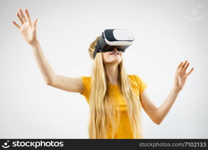 Young woman wearing virtual reality goggles headset, vr box, stretching arms. Connection, technology, new generation and progress concept. Studio shot on gray. Girl wearing virtual reality goggles.