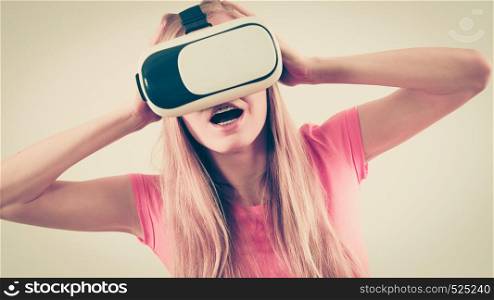 Young woman wearing virtual reality goggles headset, vr box. Studio shot on gray. Girl wearing virtual reality goggles.