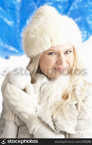Young Woman Wearing Warm Winter Clothes And Fur Hat Holding Snowball In Studio