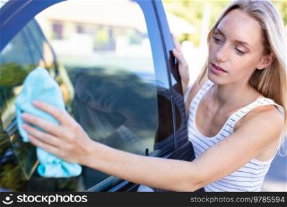 young woman wiping her car with microfiber cloth