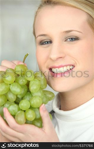 Young woman with a bunch of green grapes