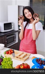 young woman with a chocolate donut in hand, kitchen room