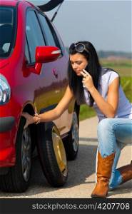 young woman with a flat tire in car