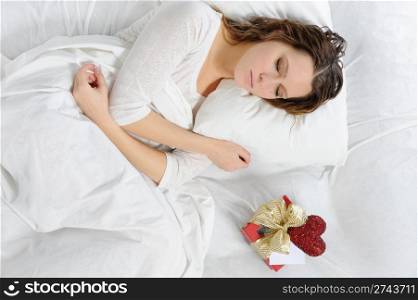 young woman with a gift box in the bed