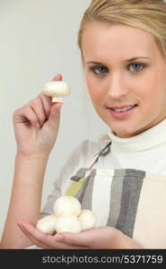 Young woman with a handful of button mushrooms