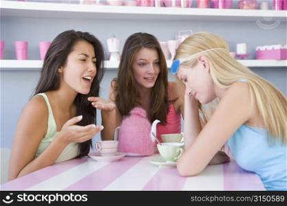 Young woman with a hangover sitting at a table with two friends